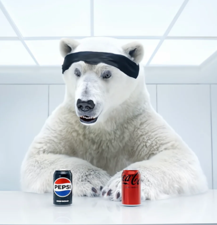 A polar bear wearing a black headband sitting at a table with a can of Pepsi and a can of Coca-Cola in front of it.