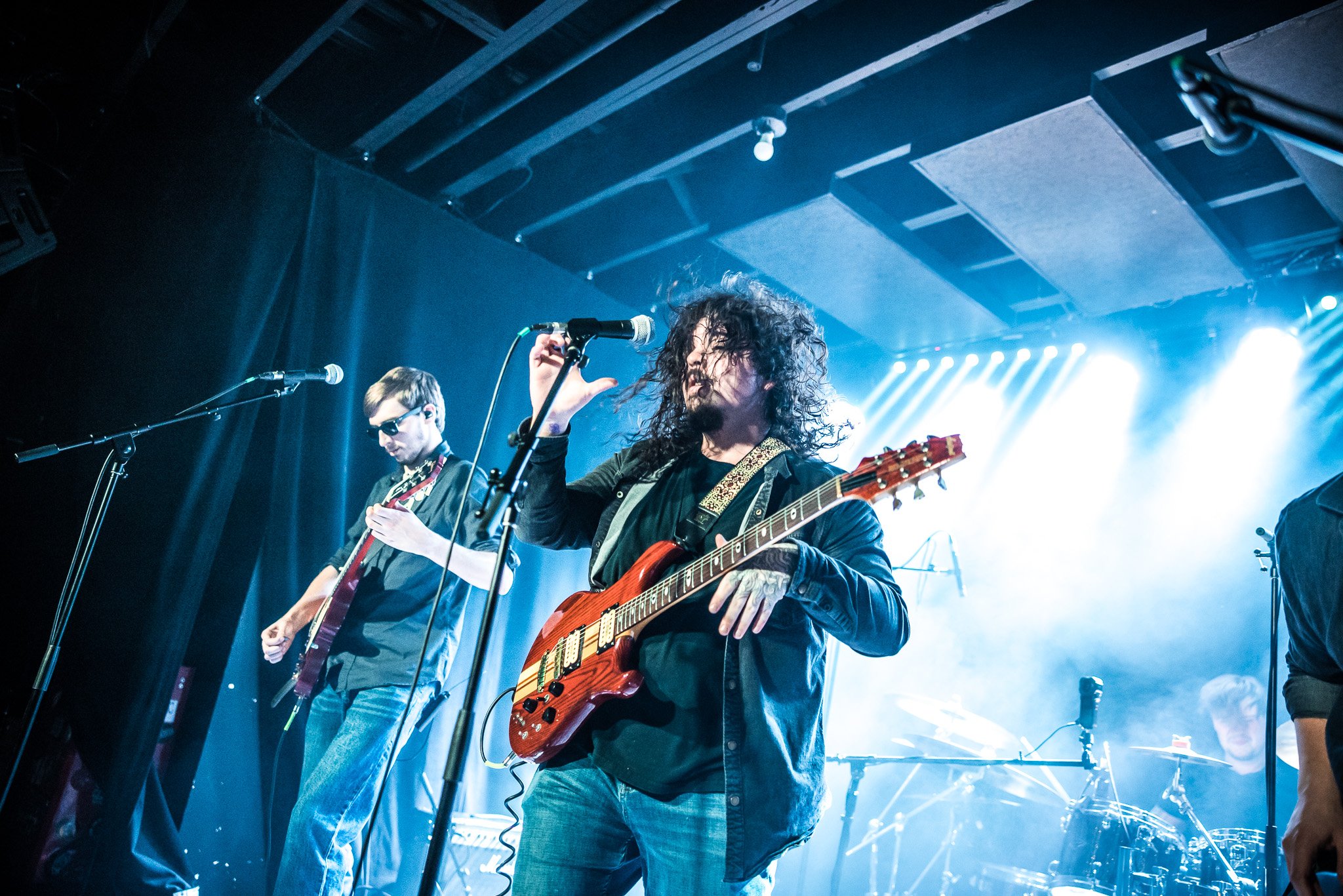 Picture of man with long hair playing guitar and singing on stage