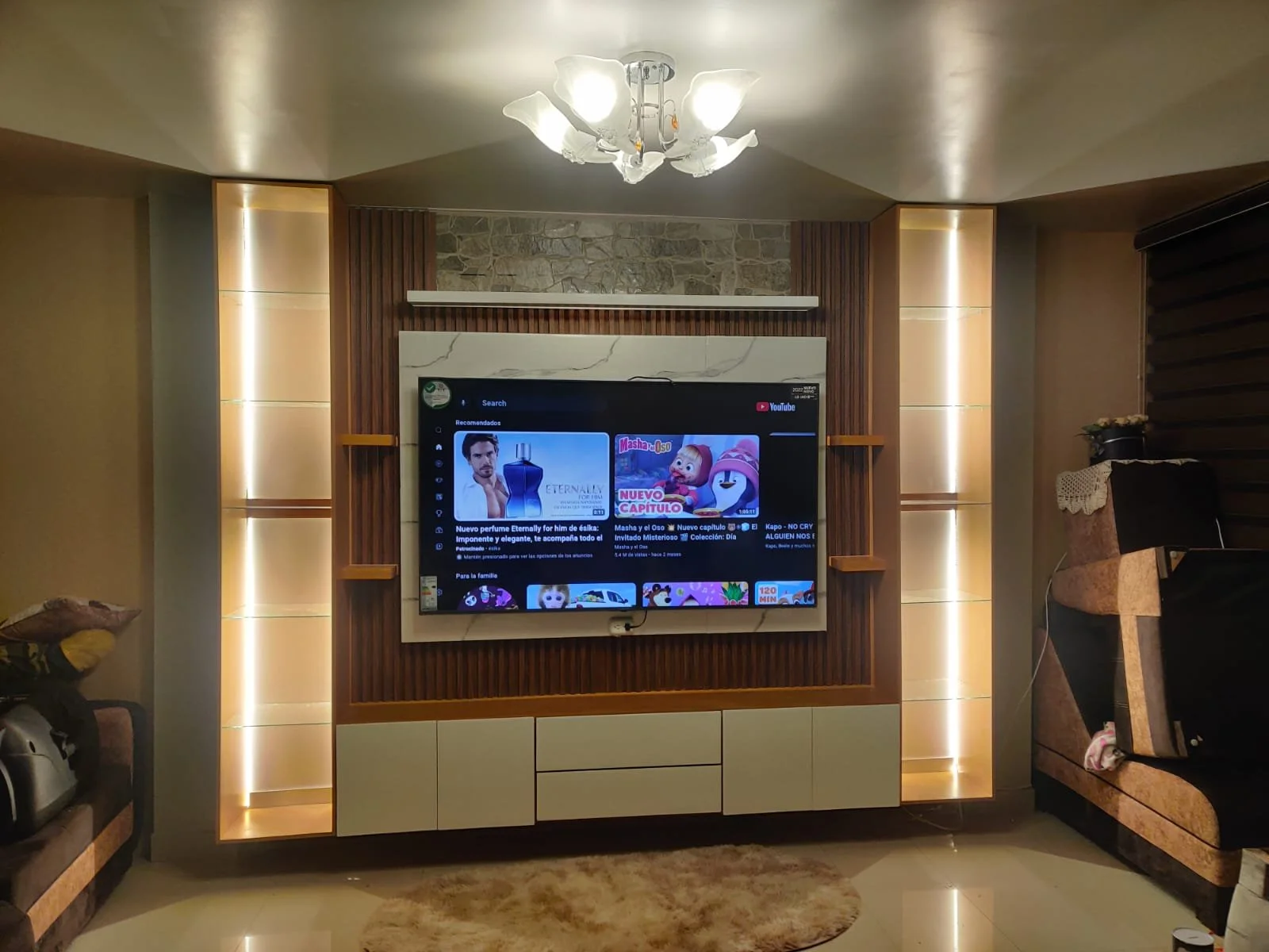 Sala de estar con televisión en la pared, luces empotradas y muebles en tonos neutros.