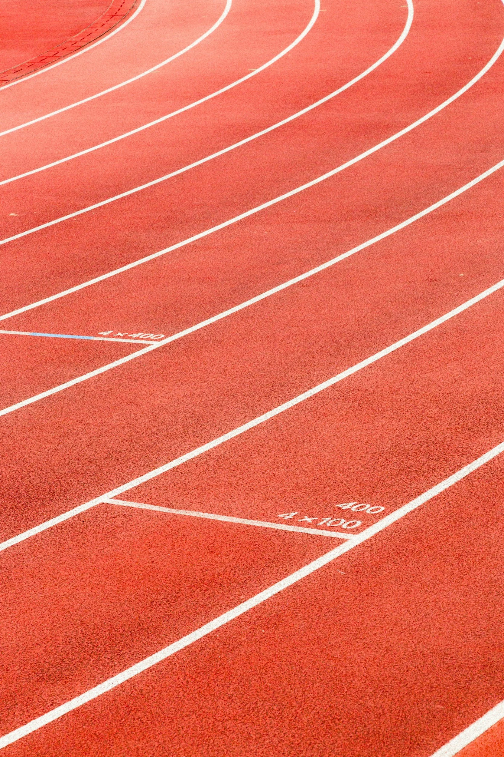 Close-up of a red running track with white lines, lane markings, and distance measurements.