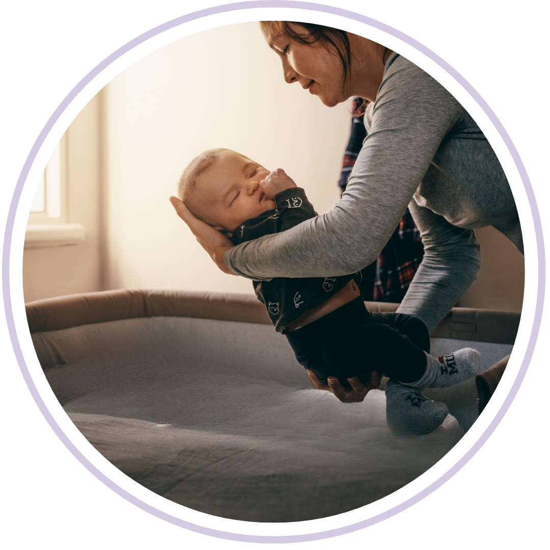 Mother picking sleeping baby up out of crib during gentle sleep training session