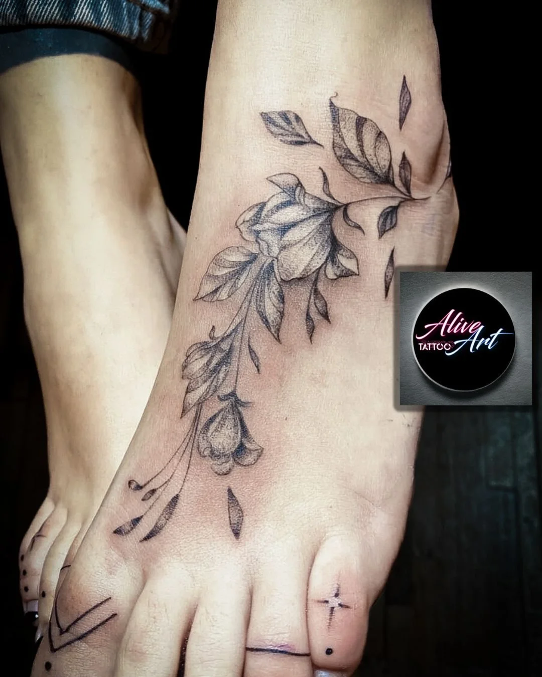 A tattoo of a detailed floral design with leaves and a rose, located on the hand and wrist.