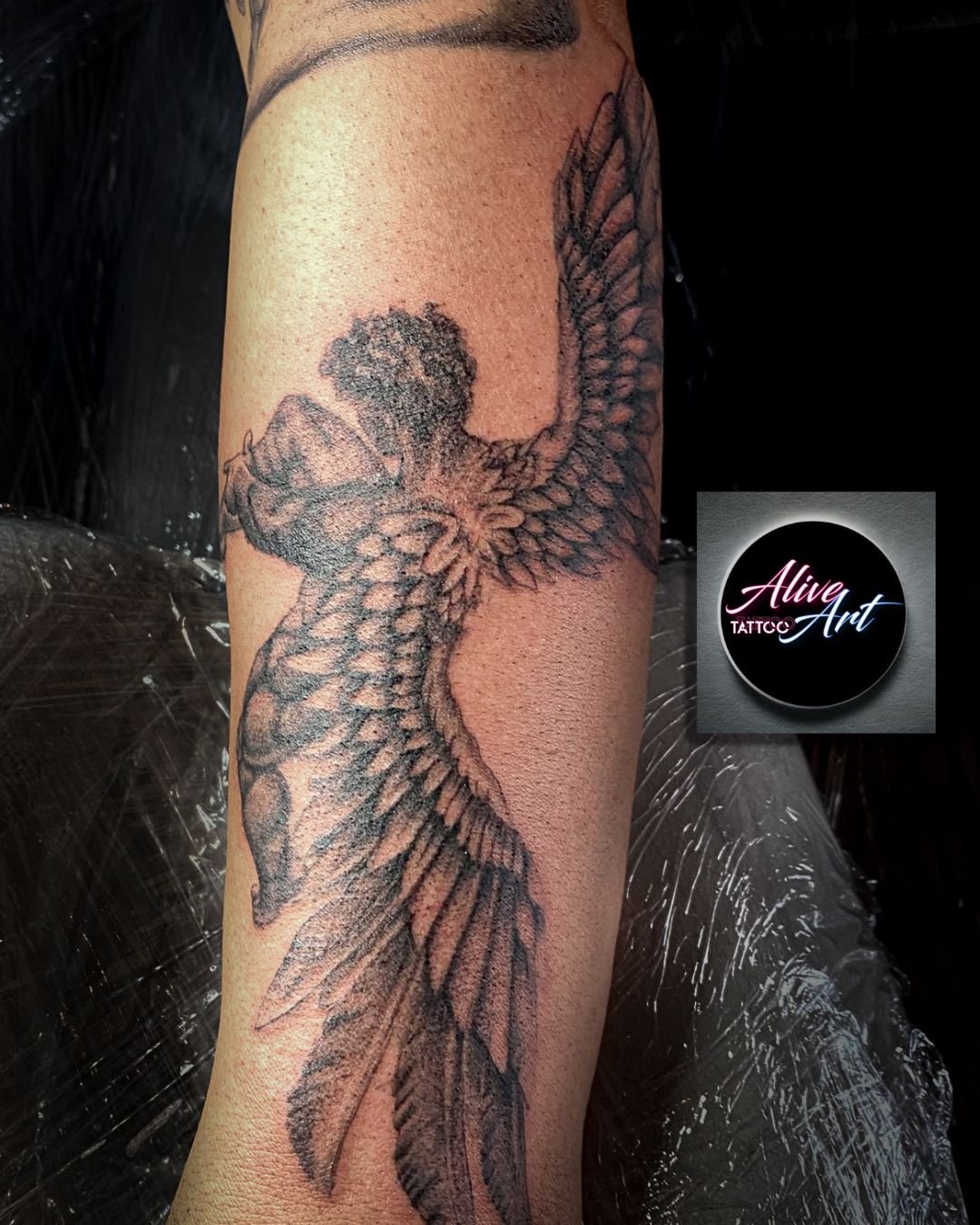 Black and gray tattoo of a bird in flight on a person's arm, featuring detailed feathers and a textured body.
