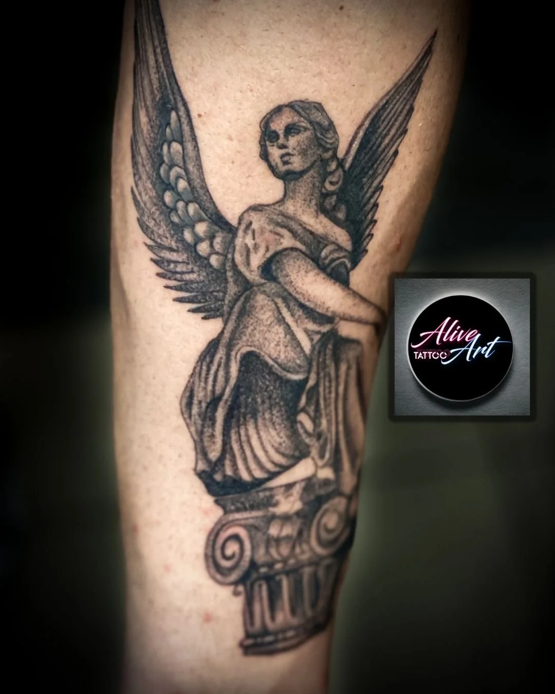 Black and gray tattoo of an angel with wings, seated on a classical column, on a person's arm.