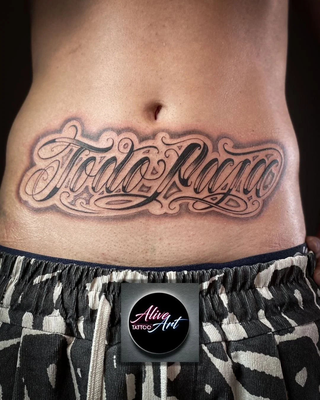 Tattoo on a person's lower abdomen that says 'Stay Positive' in decorative script.