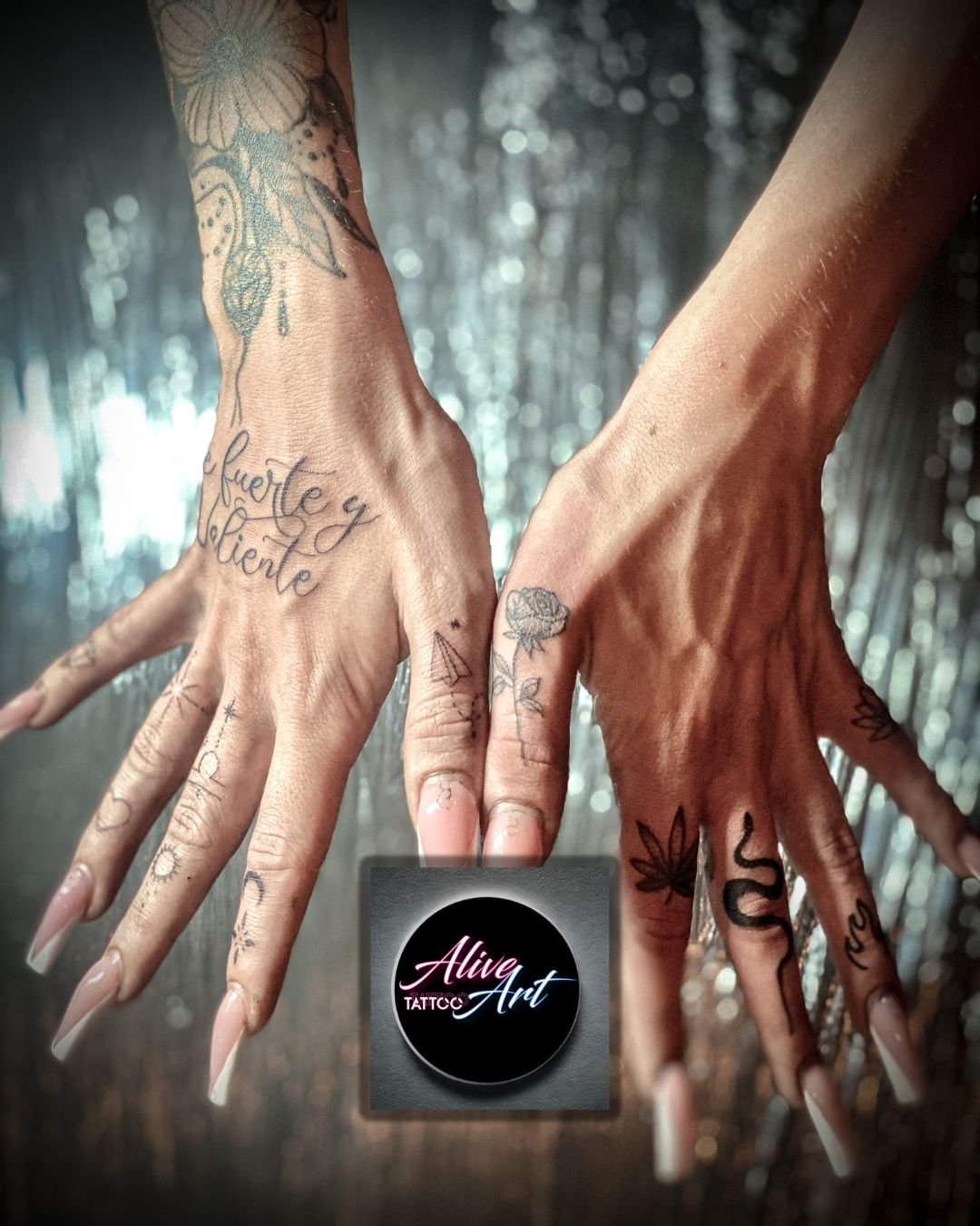 Two hands with tattoos reaching towards each other against a blurred background. The left hand has a large flower and the words 'fuerte y silencie' tattooed on it. The right hand has tattooed herbs and a snake on the fingers.