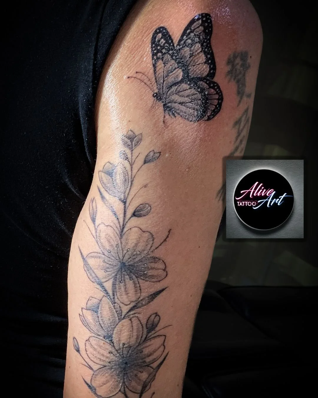 Tattoo of a butterfly and floral design on a person's upper arm.