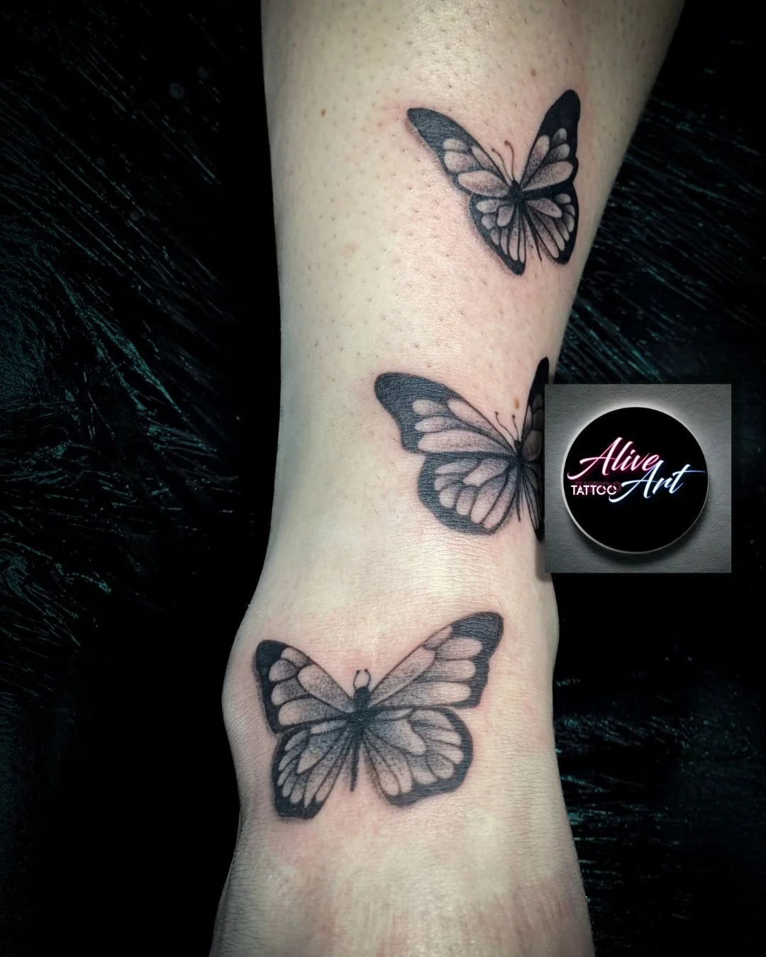 Black and gray butterfly tattoos on a person's arm