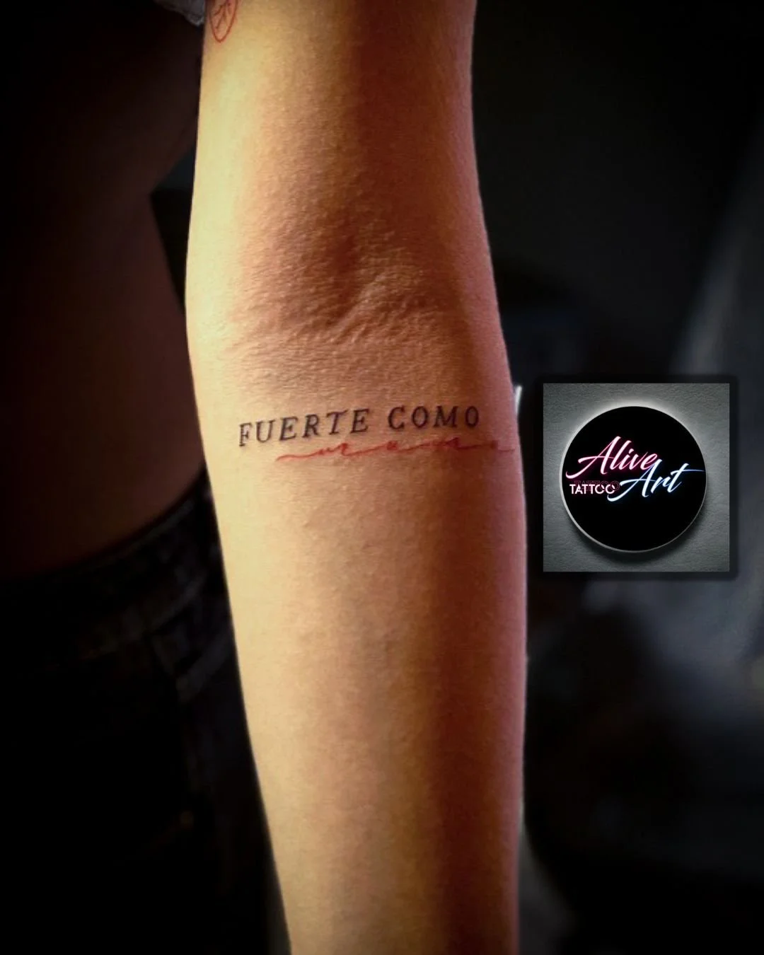 Tattoo on person's inner forearm with the words "FUERTE COMO" and a red underline.