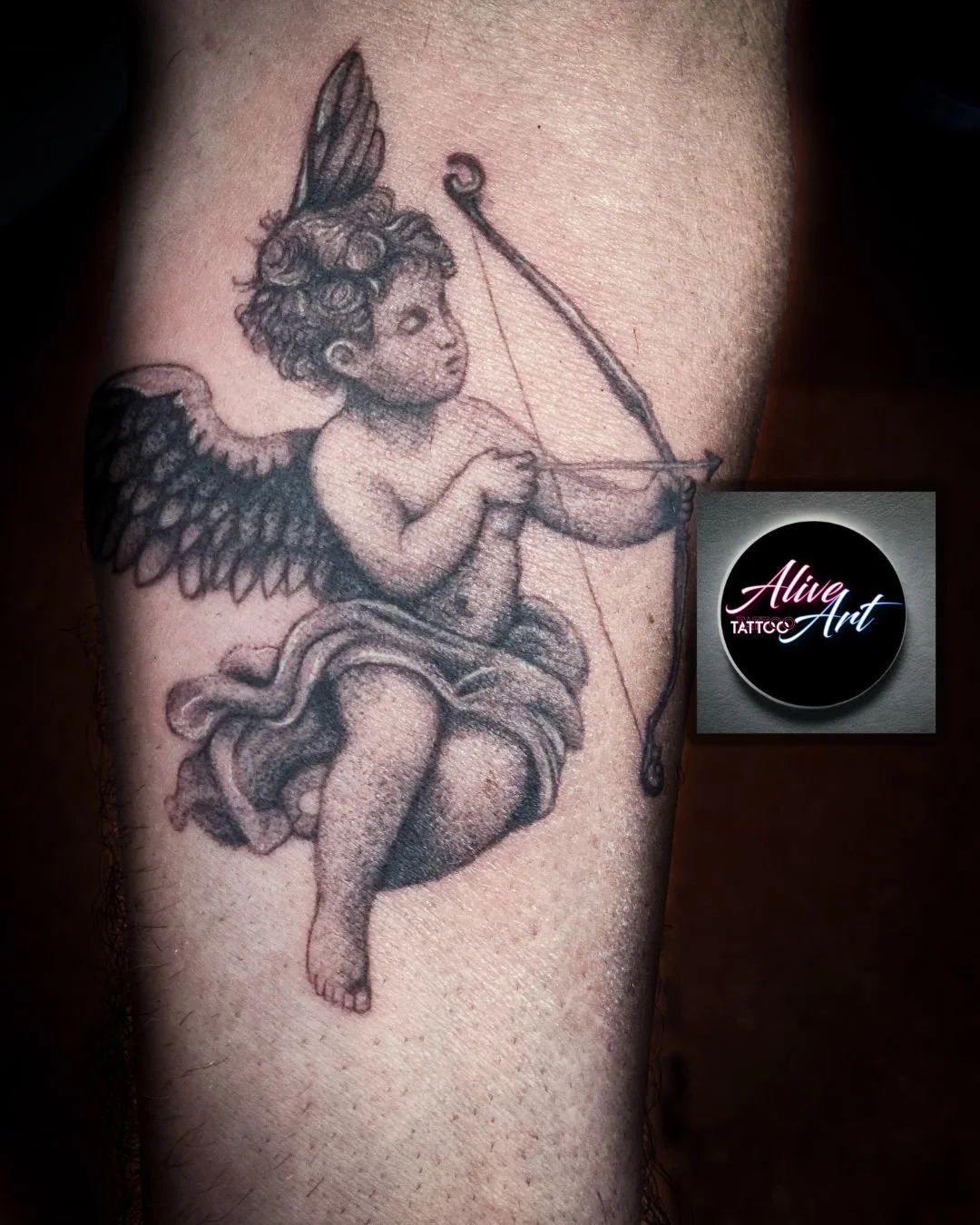Tattoo of a cherub with wings, sitting on a crescent moon, holding a bow and arrow.
