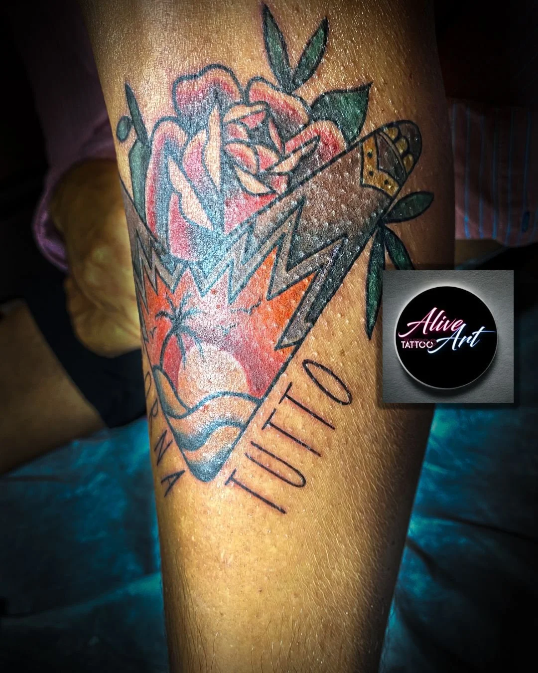 Colorful tattoo on arm featuring flowers, lightning bolts, a cassette tape, and the word 'UTD'.