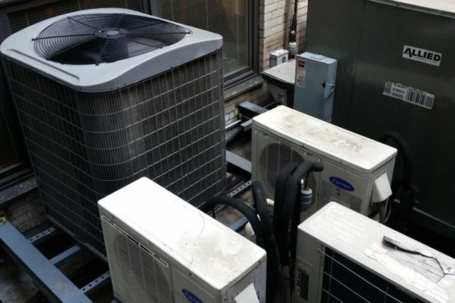 Outdoor HVAC units on a building rooftop paired with electrical boxes.