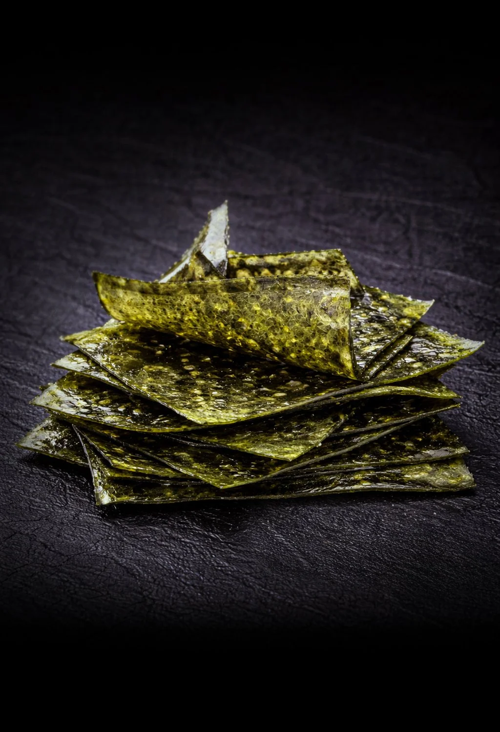 Stack of seaweed sheets on a dark textured surface.