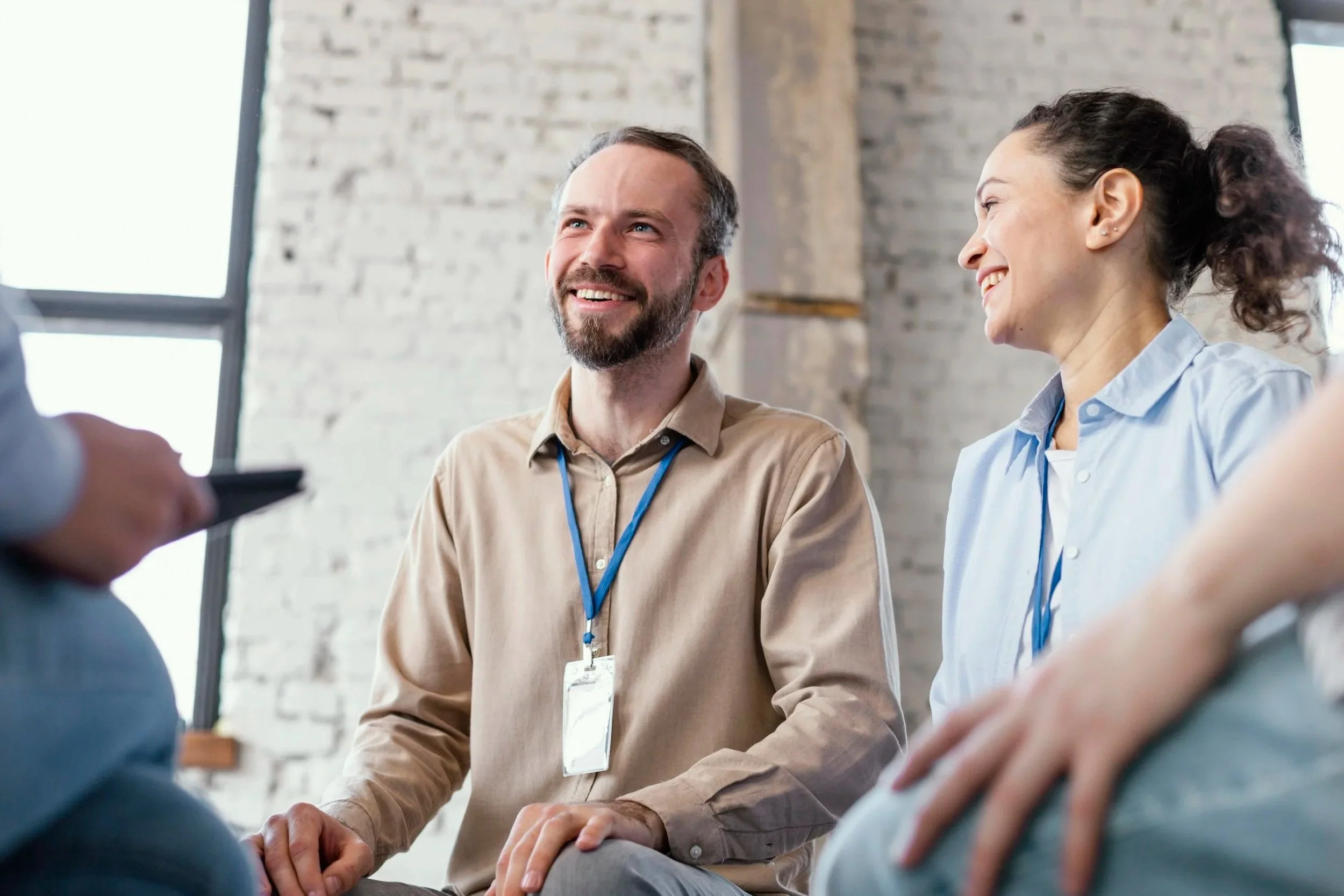 A man and a woman, smiling and engaged in conversation at a professional meeting.