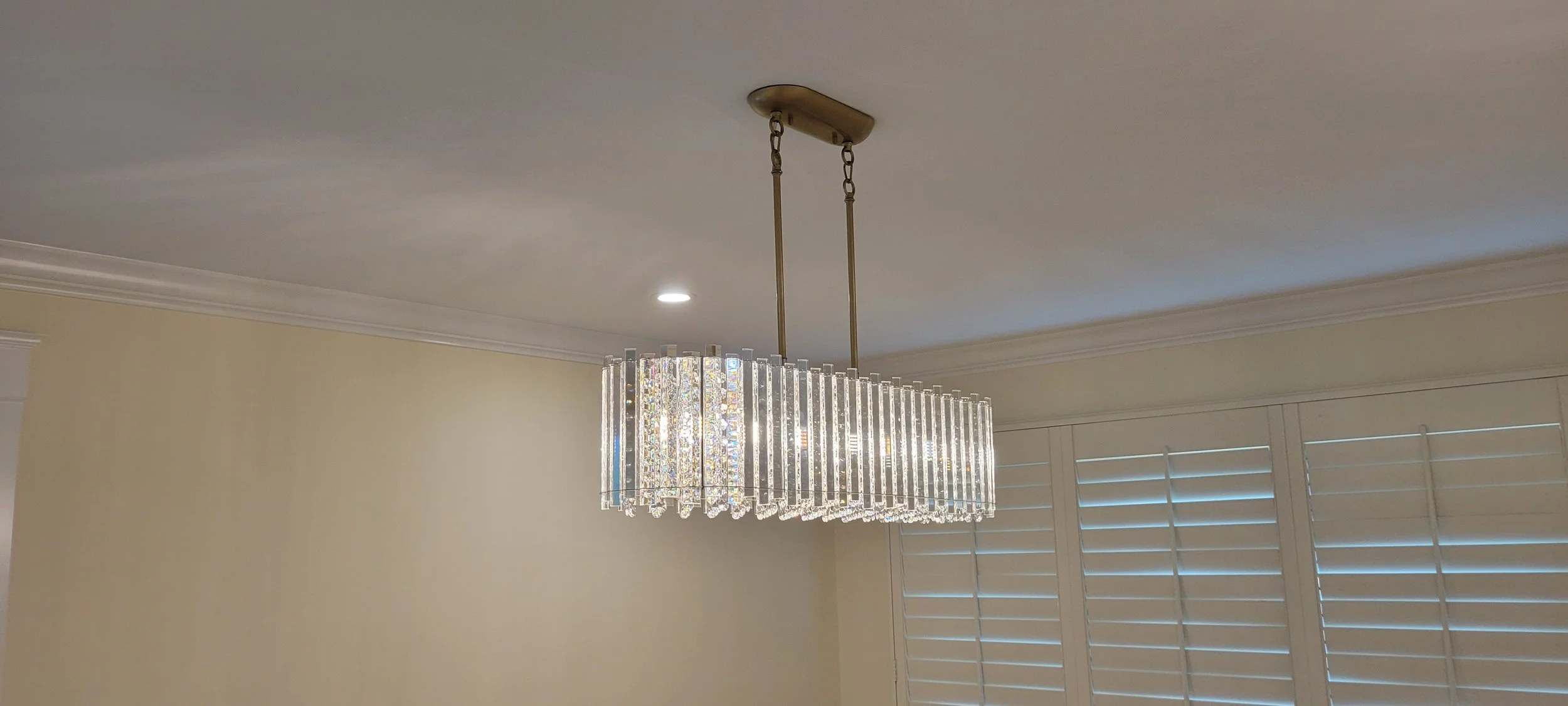 Modern crystal chandelier hanging from a ceiling in a well-lit room.