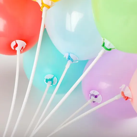 Close-up of colorful balloons in red, green, purple, blue, and yellow, attached to white sticks with colored clips.