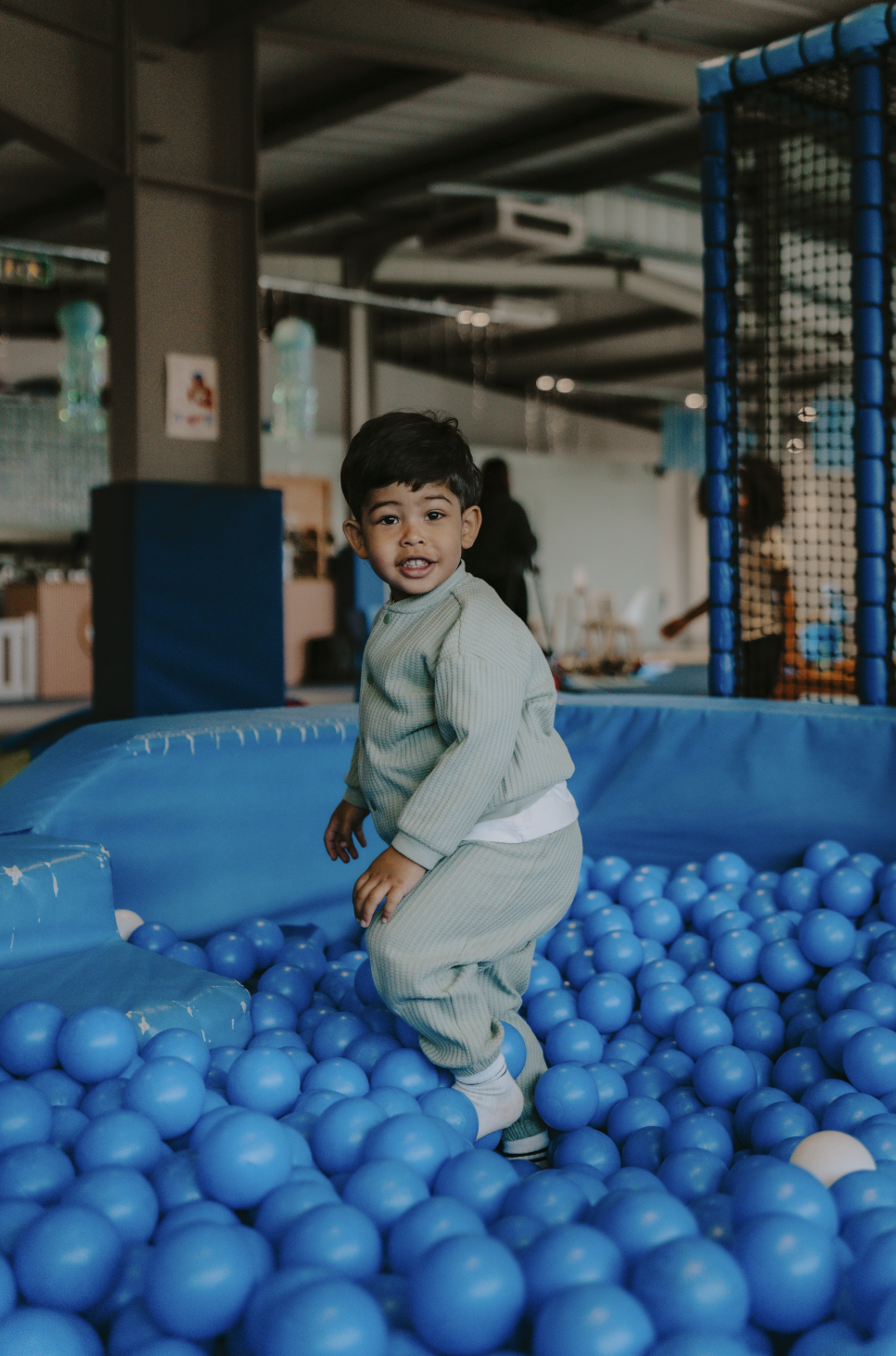 Young boy playing in a blue ball pit at an indoor play center.