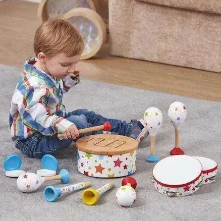 A young boy playing with colorful musical instruments, including maracas, drums, and a shaker, on a carpeted floor in a living room.