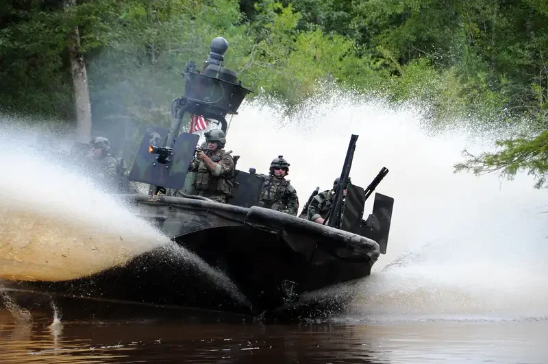 Military boat with soldiers navigating through water.
