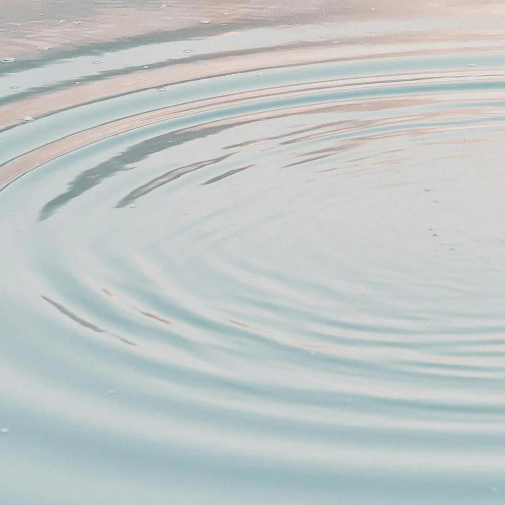 Close-up of water surface with ripples and gentle colors reflecting the sky.