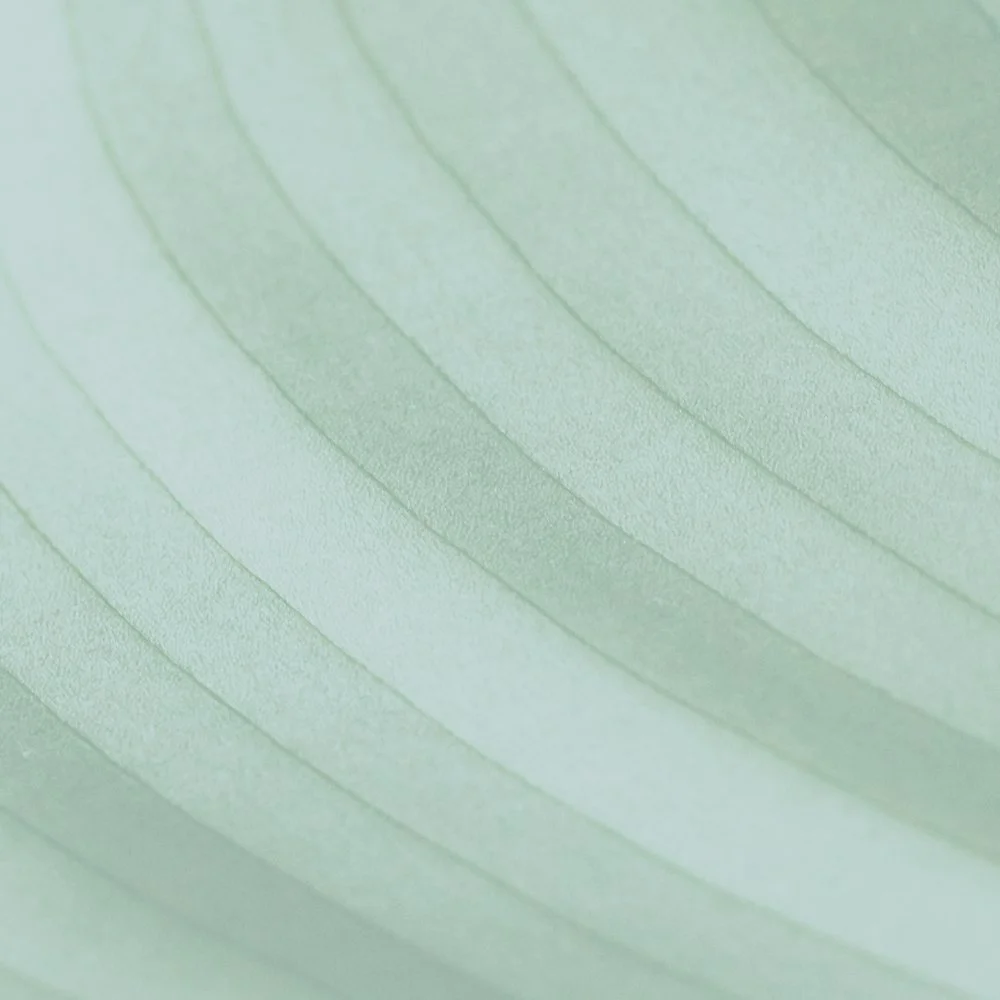 Close-up of a light green surface with embossed curved lines.