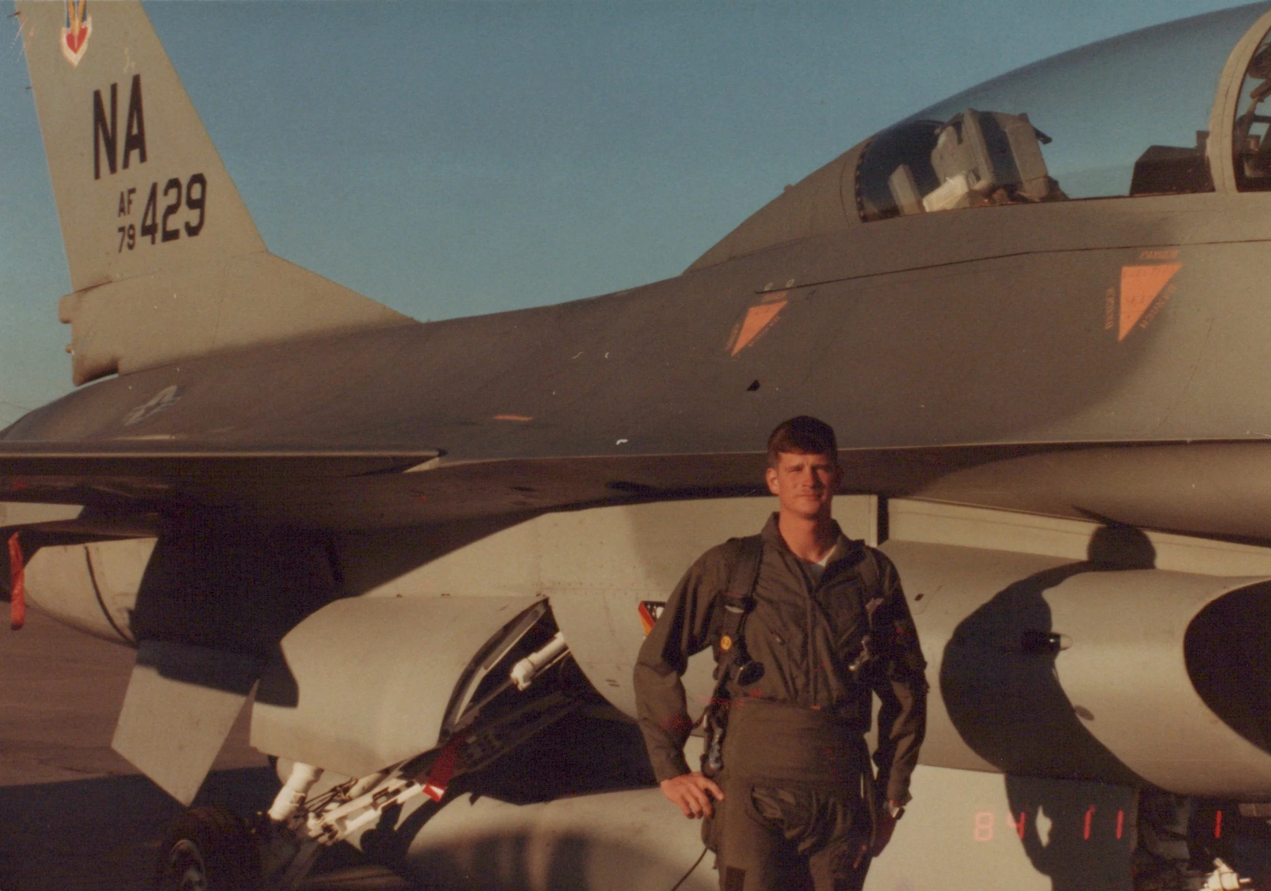 Craig's father dressed in a flight suit in front of an F-16 fighter jet before his incentive flight in 1984