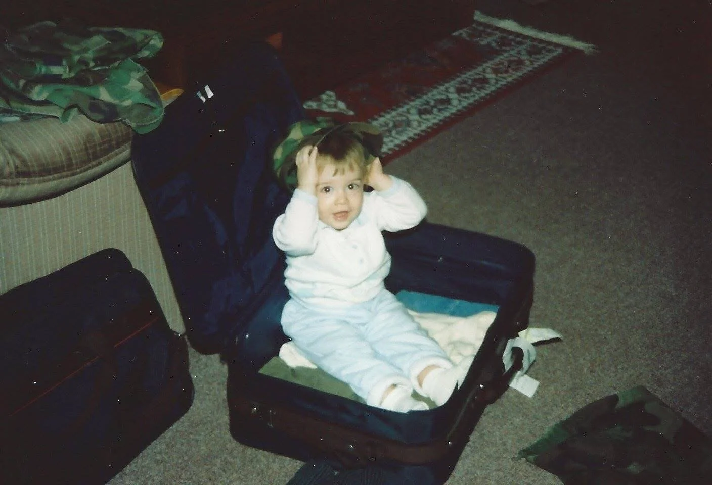 Baby Craig sitting in a suitcase while his father packs for a military TDY abroad