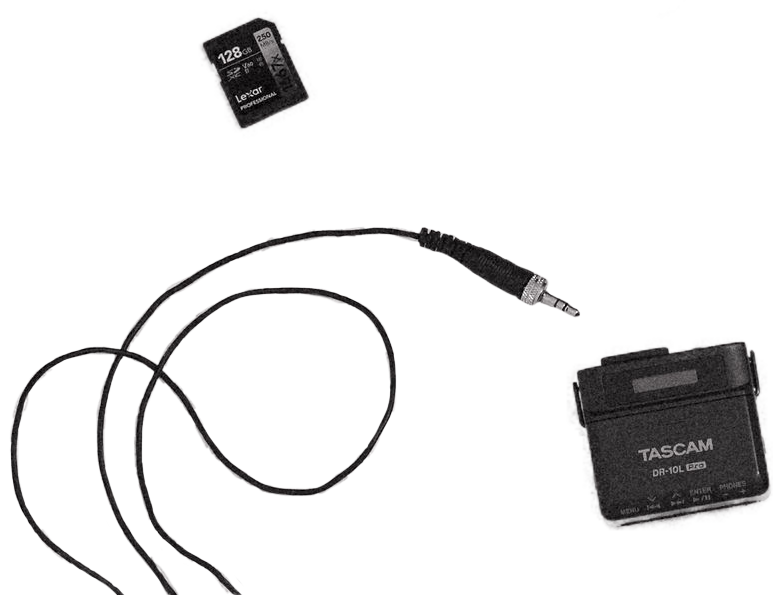 A Tascam audio recorder, a 128GB SD card, an XLR microphone cable, and a compact black Tascam DR-10L Pro voice recorder on a light gray surface.
