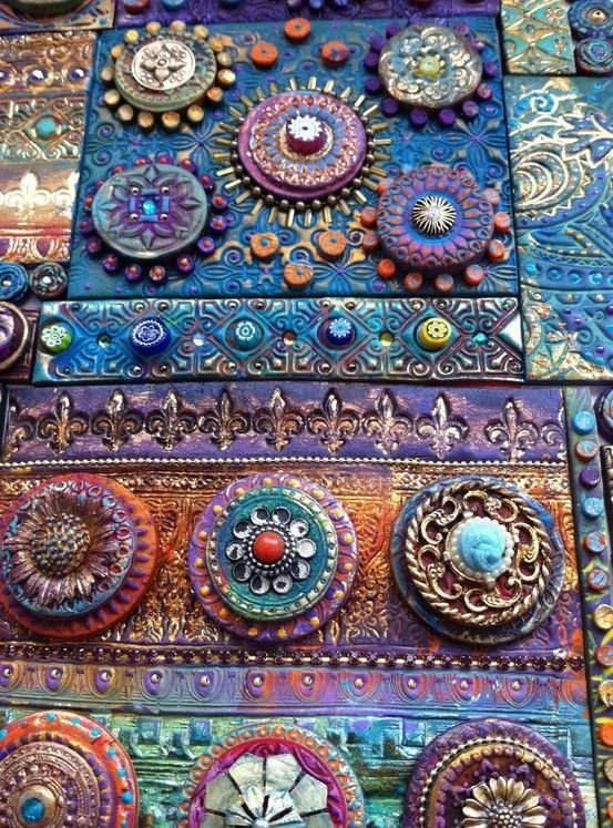 Close-up of a colorful, decorative mosaic made from various textured and patterned ceramic pieces, beads, and embellishments arranged in intricate designs.