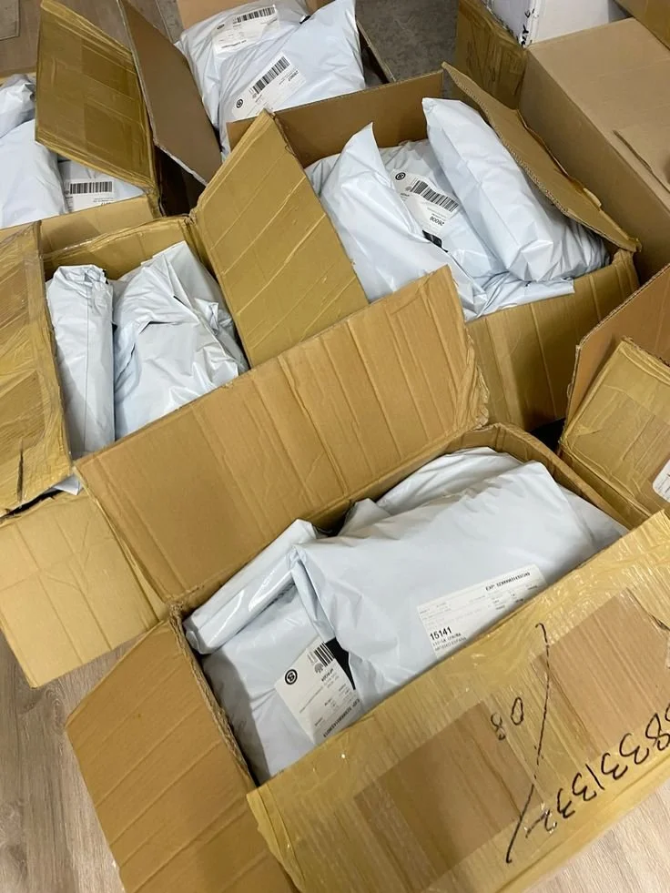Multiple open cardboard boxes filled with white padded shipping envelopes.