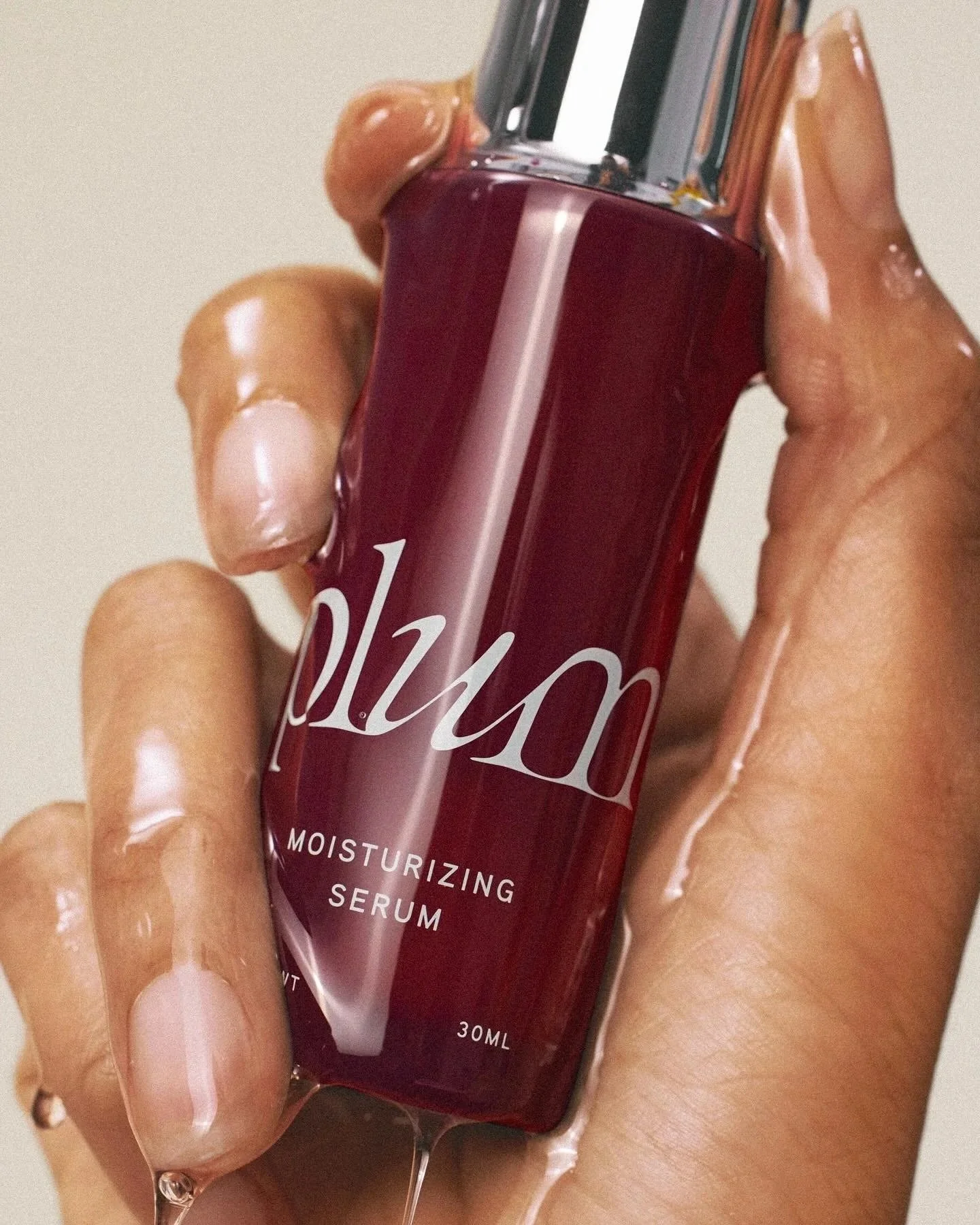 Close-up of a hand holding a small bottle labeled 'moisturizing serum' with a transparent dropper on top.