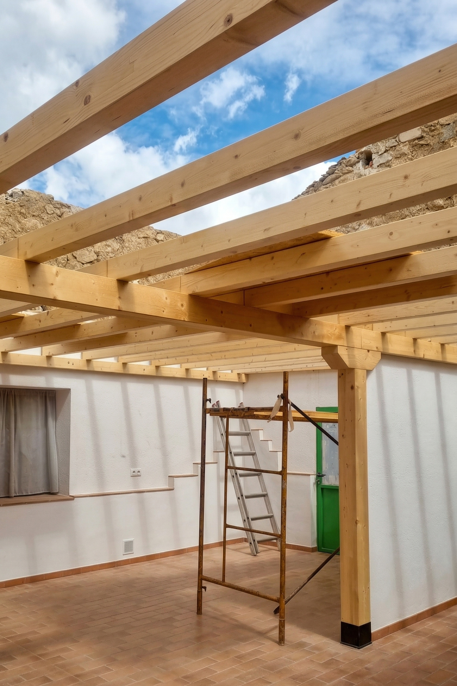 Interior of a house under construction with exposed wooden beams for a new floor or roof, scaffolding, ladder, and construction tools, with a window and a green door visible.