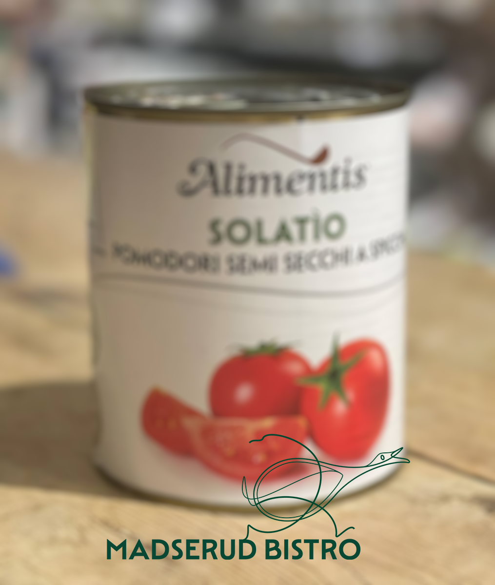 Can of tomato puree with labeled brand 'Aliments Solatio' and images of tomatoes on it, placed on a wooden surface with the text 'Madserud Bistro' at the bottom.