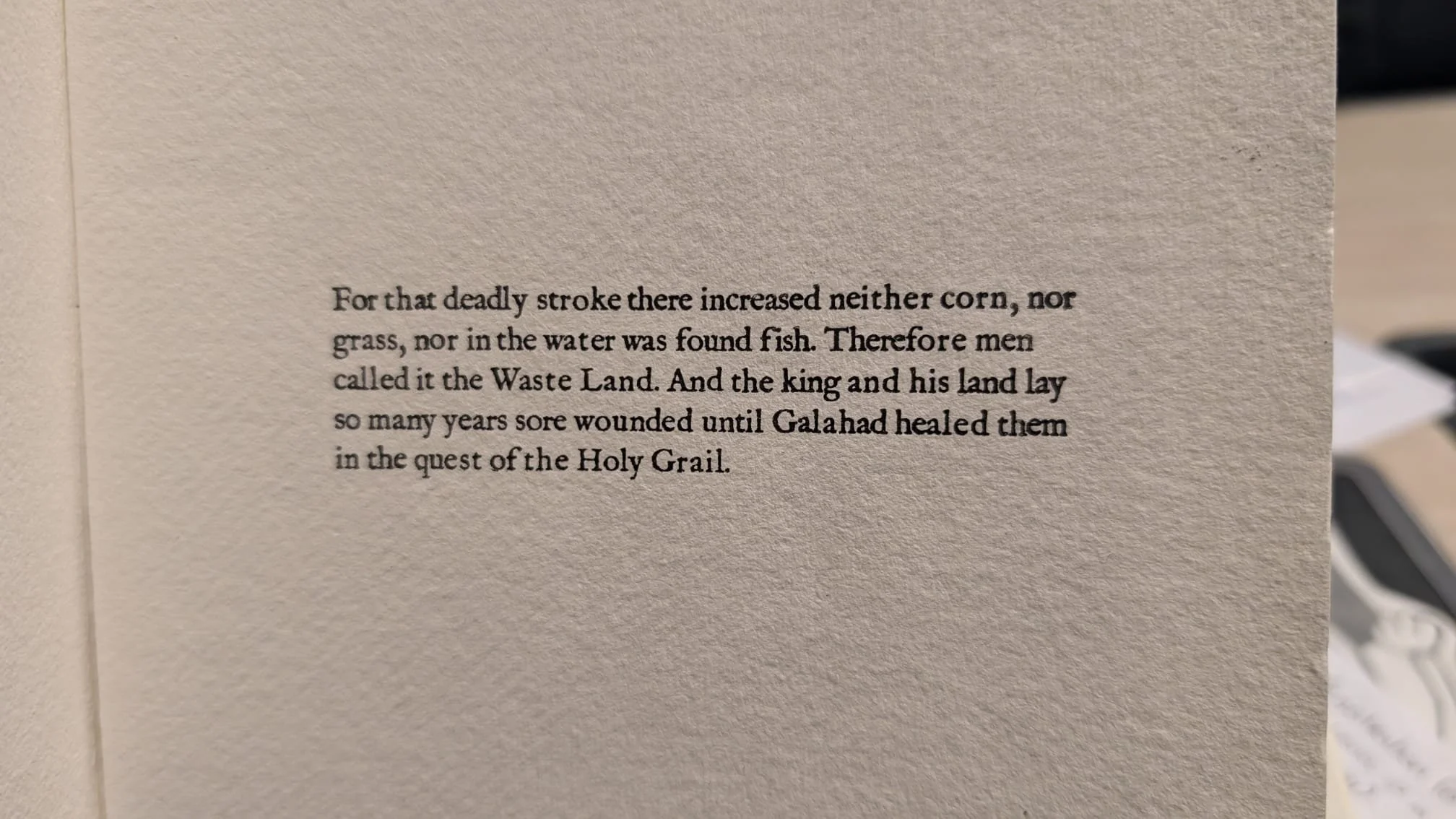 A close-up of a printed page with text about a story involving a king, land, and healing in the Holy Grail.