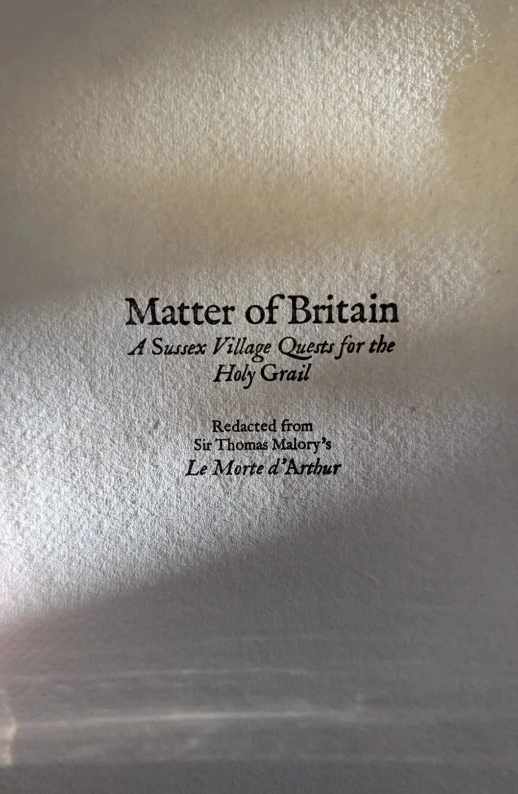 Page from a book titled "Matter of Britain: A Sussex Village Quest for the Holy Grail," adapted from Sir Thomas Malory's "Le Morte d'Arthur."