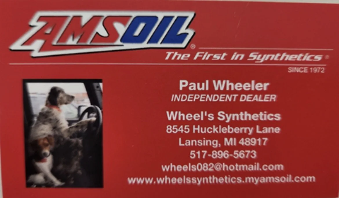 Business card for Wheels Synthetics with contact information, a logo for AMSOIL, and a photo of two dogs inside a vehicle.