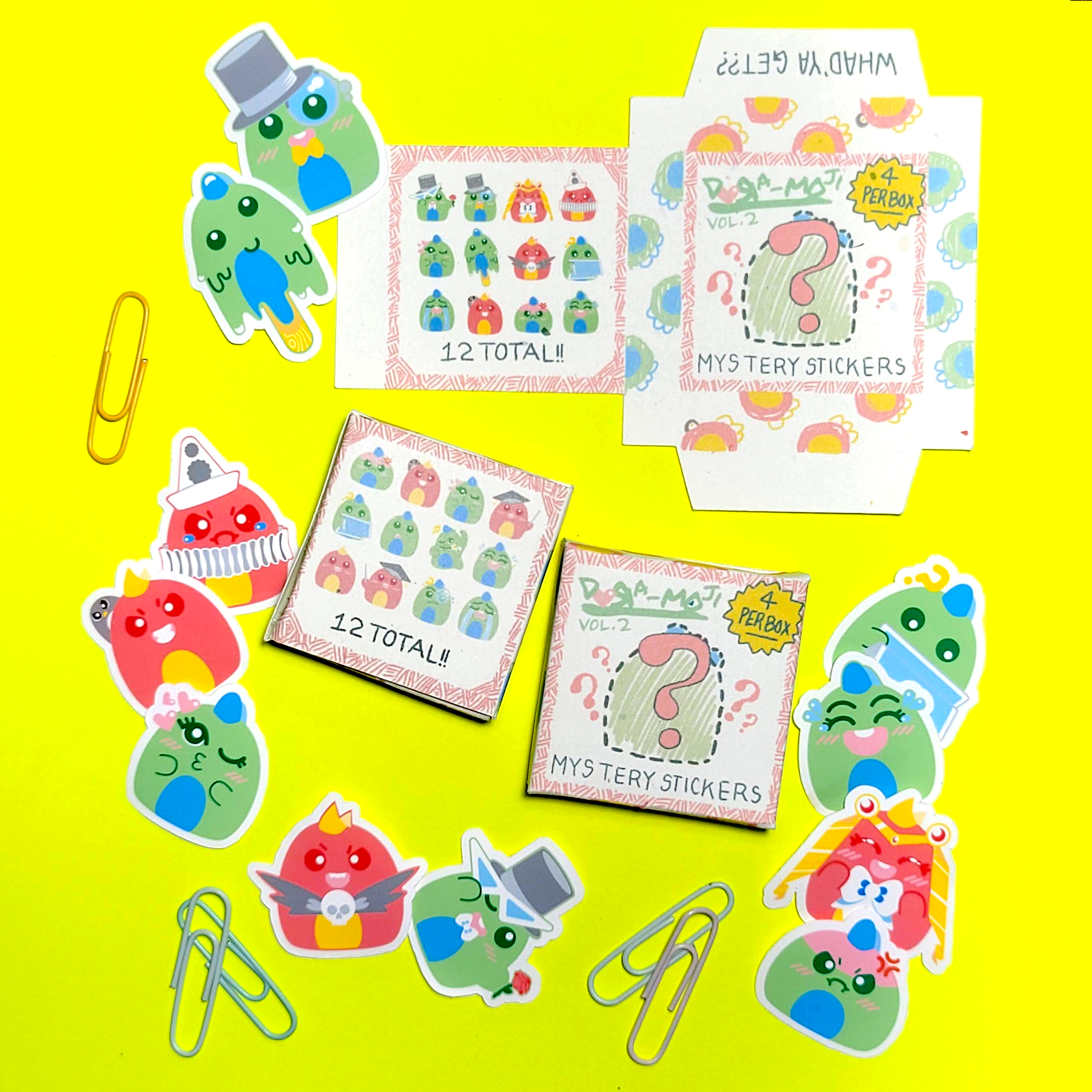 Colorful stickers featuring various cartoon characters, some dressed as royalty and others with playful expressions, scattered around on a yellow background along with paper clips, card boxes, and a sheet labeled '12 Totally' and 'Mystery Stickers'.