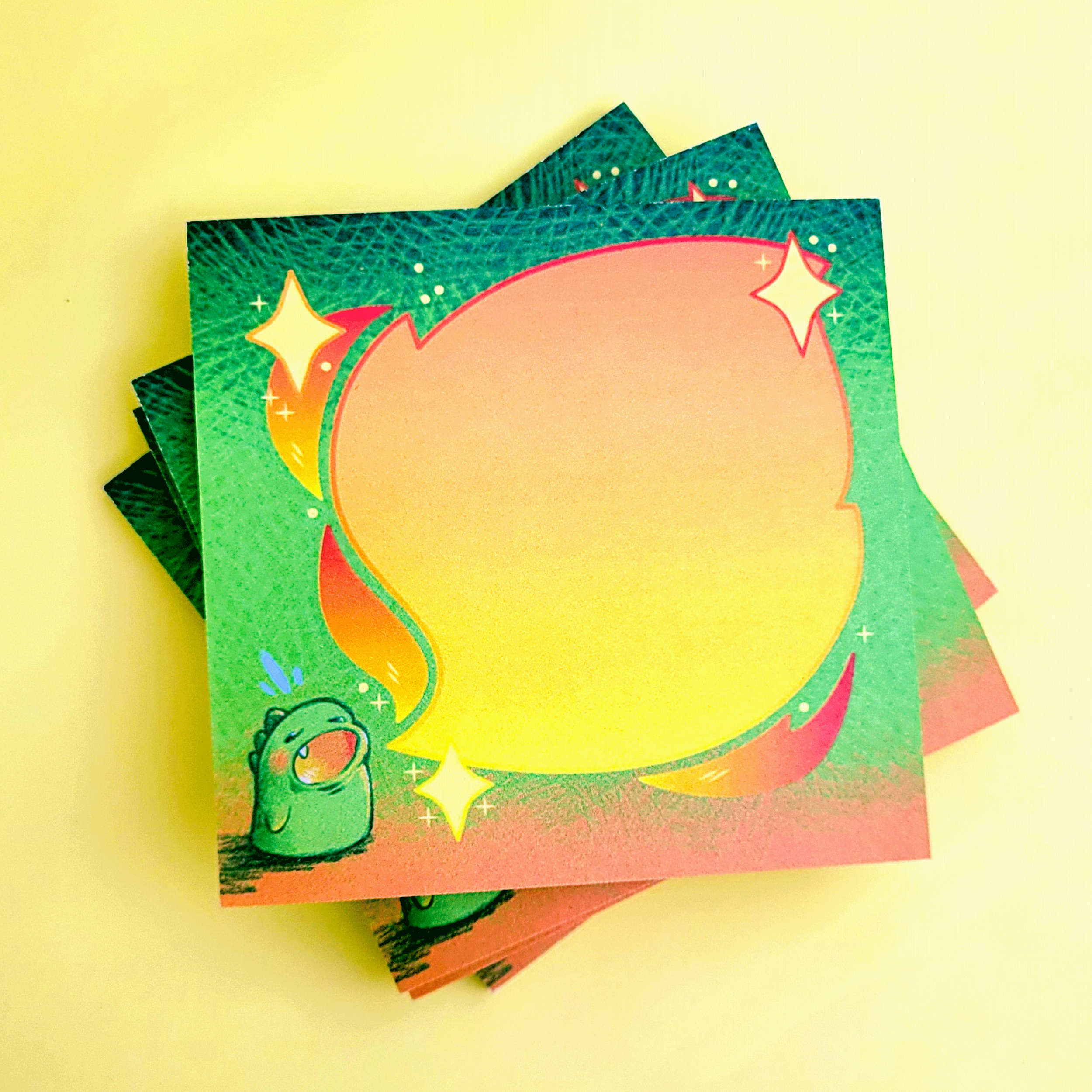 Stack of colorful sticky notes with a green cartoon creature, sparkles, and a large blank yellow speech bubble in the center.