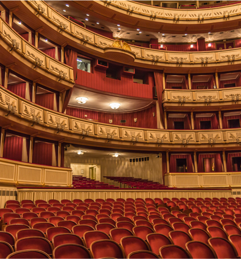 Empty theater with multiple balconies and red seats.