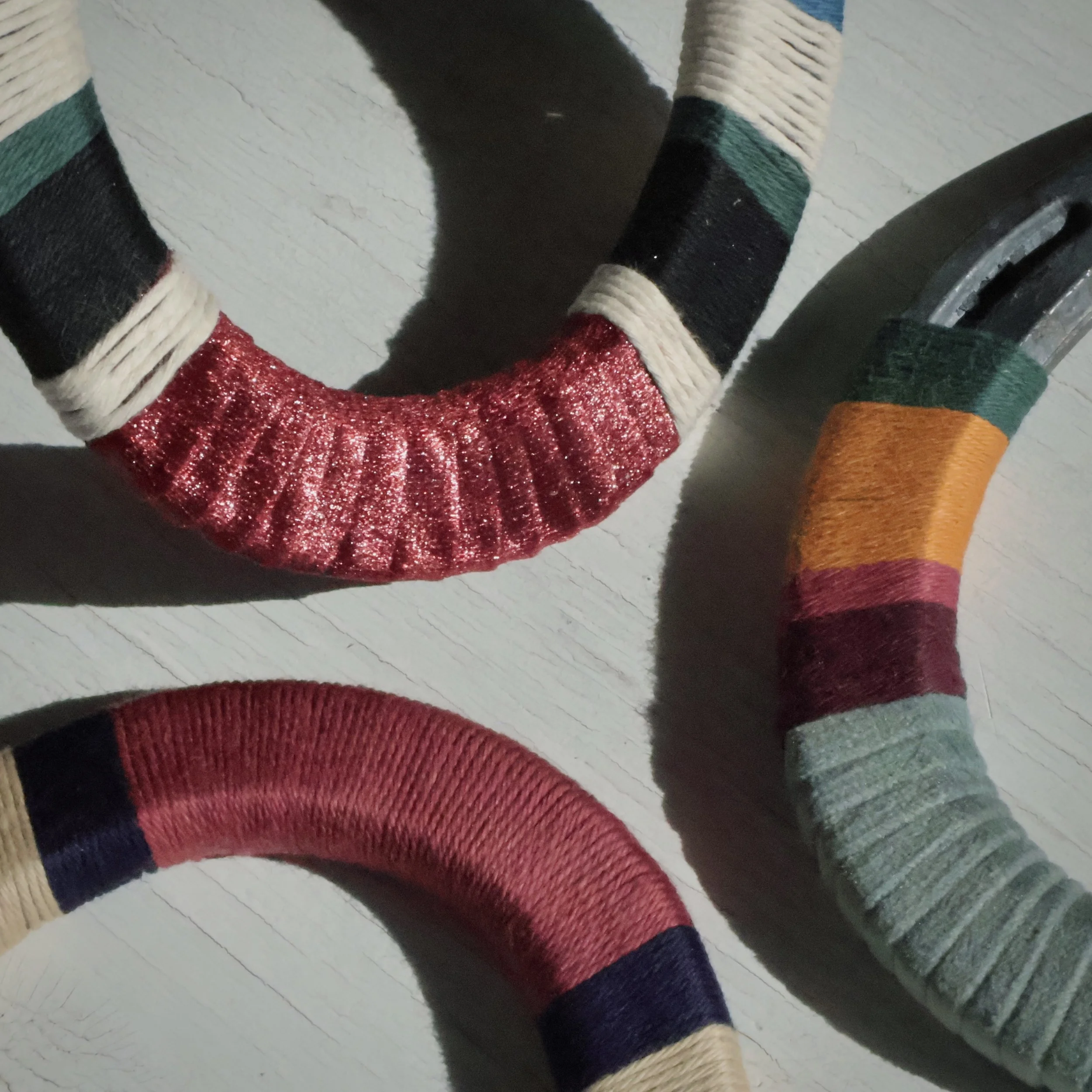 Colorful sweaters with thick yarn and striped patterns on a white wooden surface.
