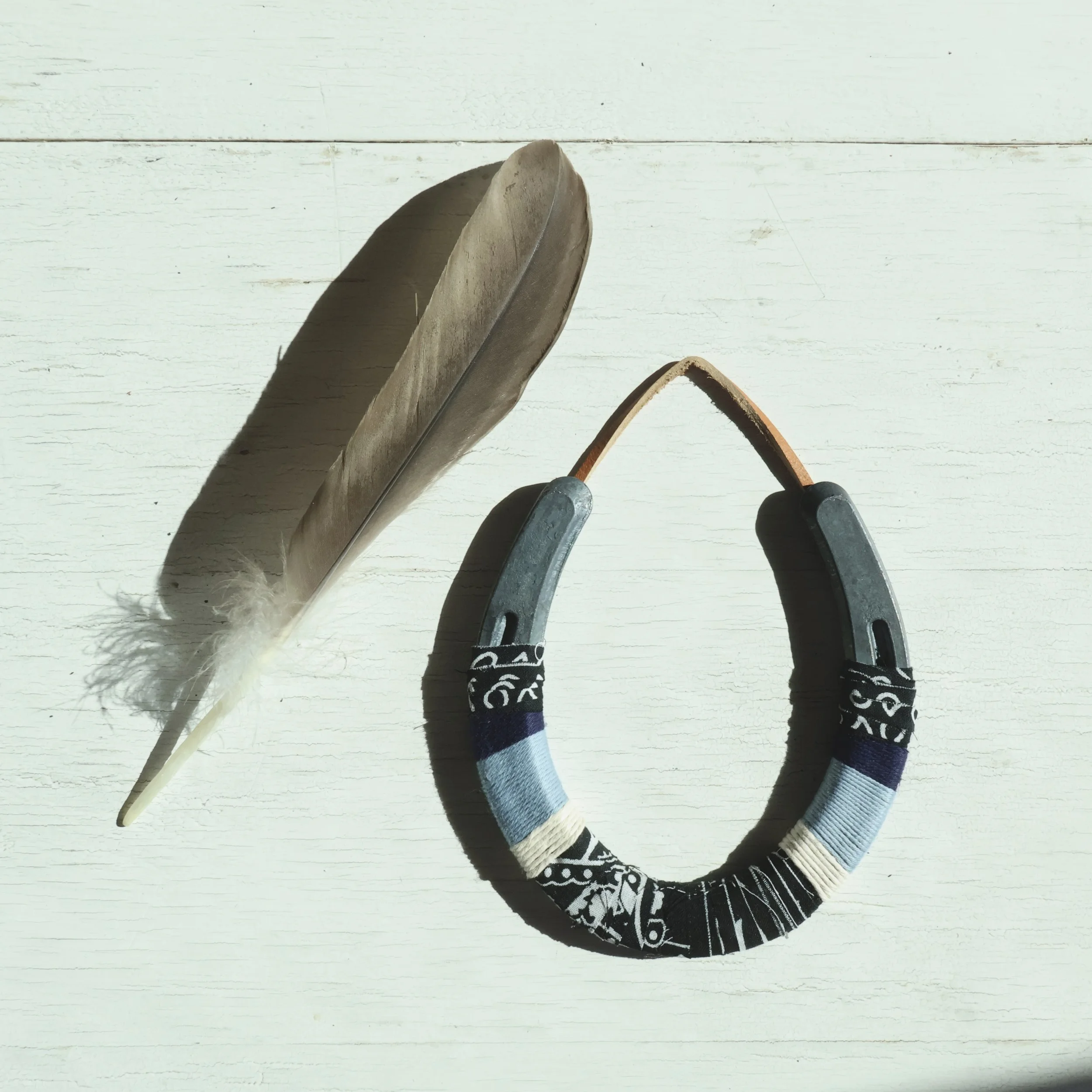 A white wooden surface with two hockey sticks crossed and a feather.