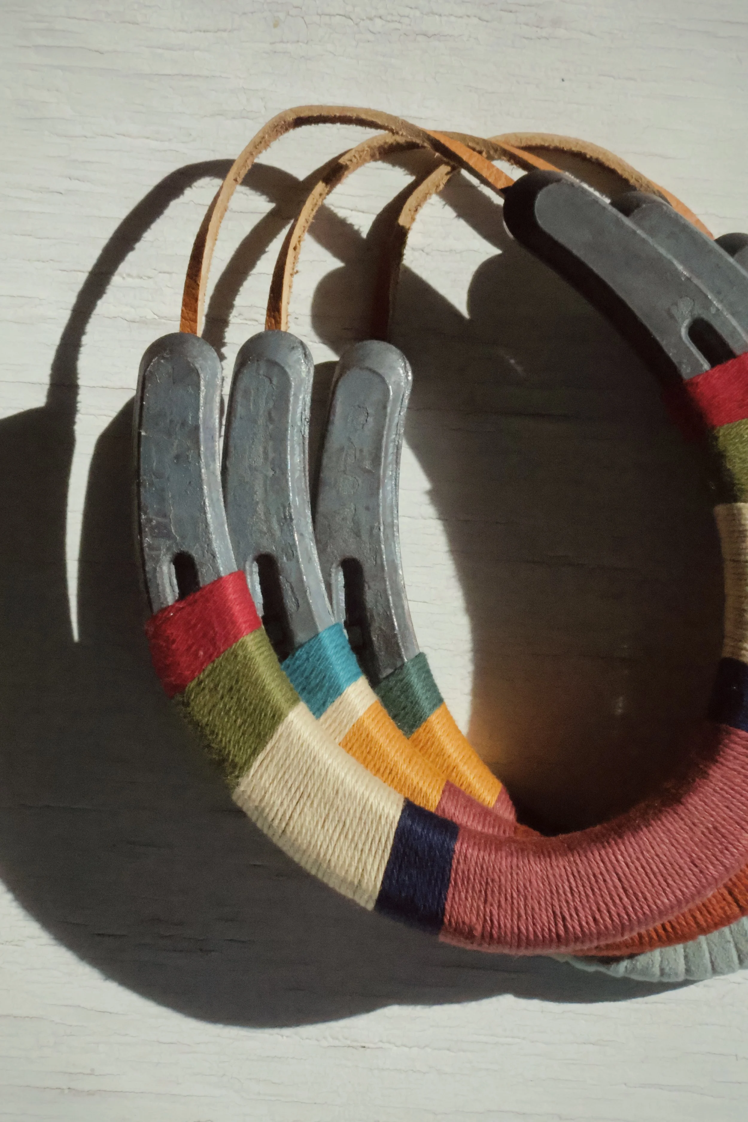 Colorful woven strap with metal hooks attached, resting on a surface.