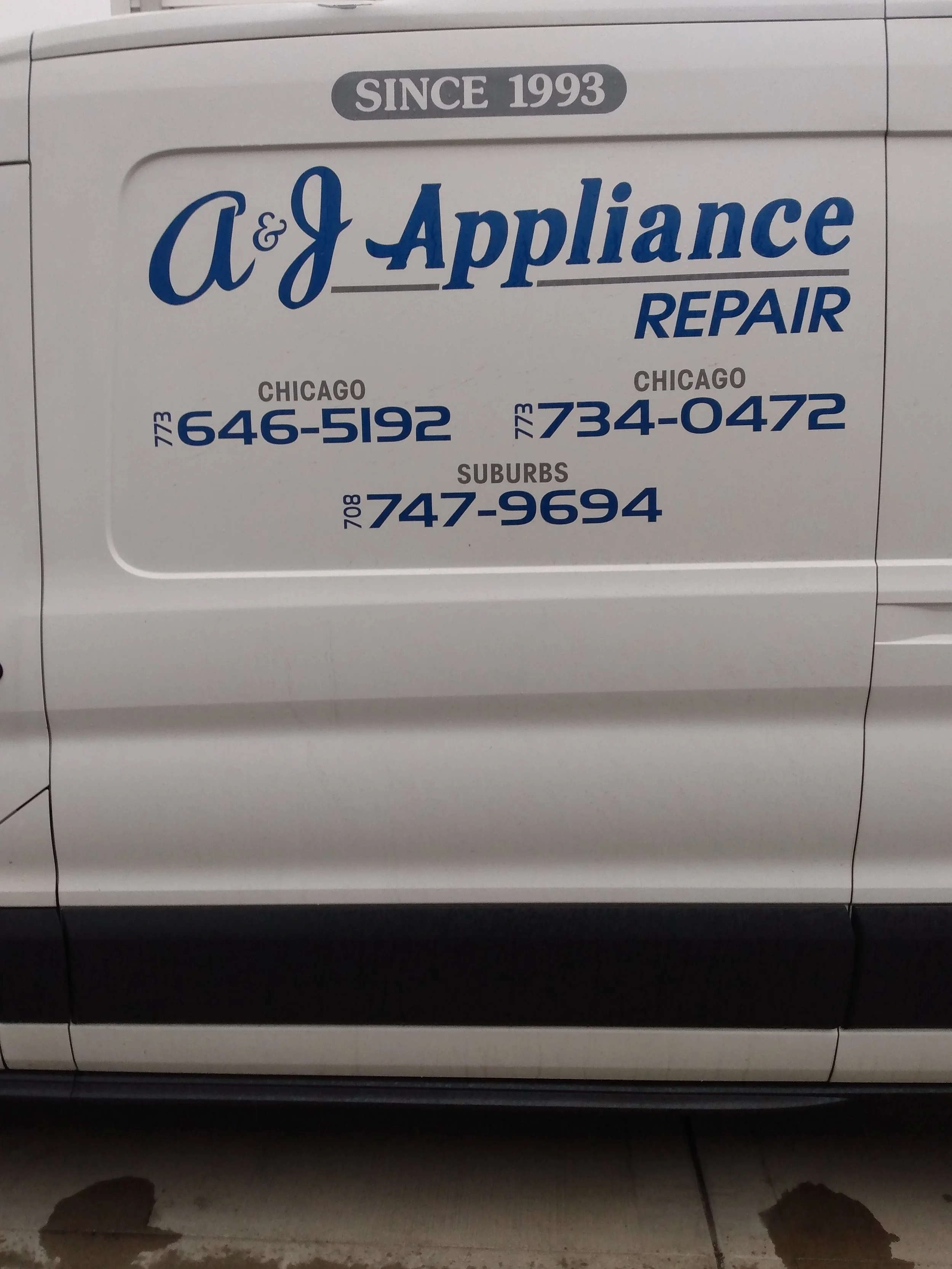 Sign on a vehicle for A&J Appliance Repair, established in 1993, with contact numbers for Chicago and suburbs.