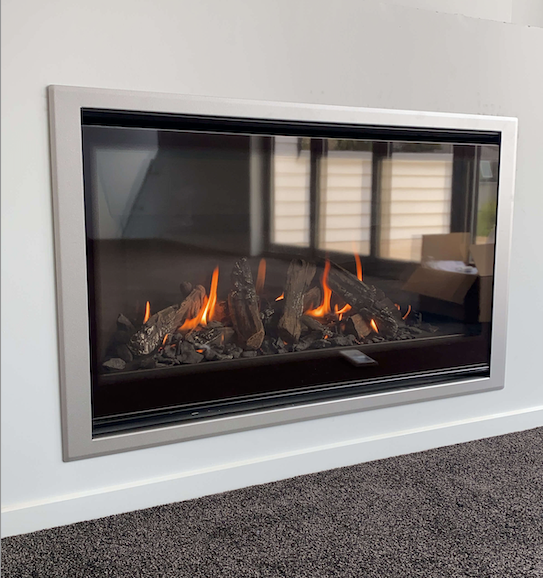 A modern electric fireplace with glowing logs and flames set into a white wall, with a carpeted floor below.