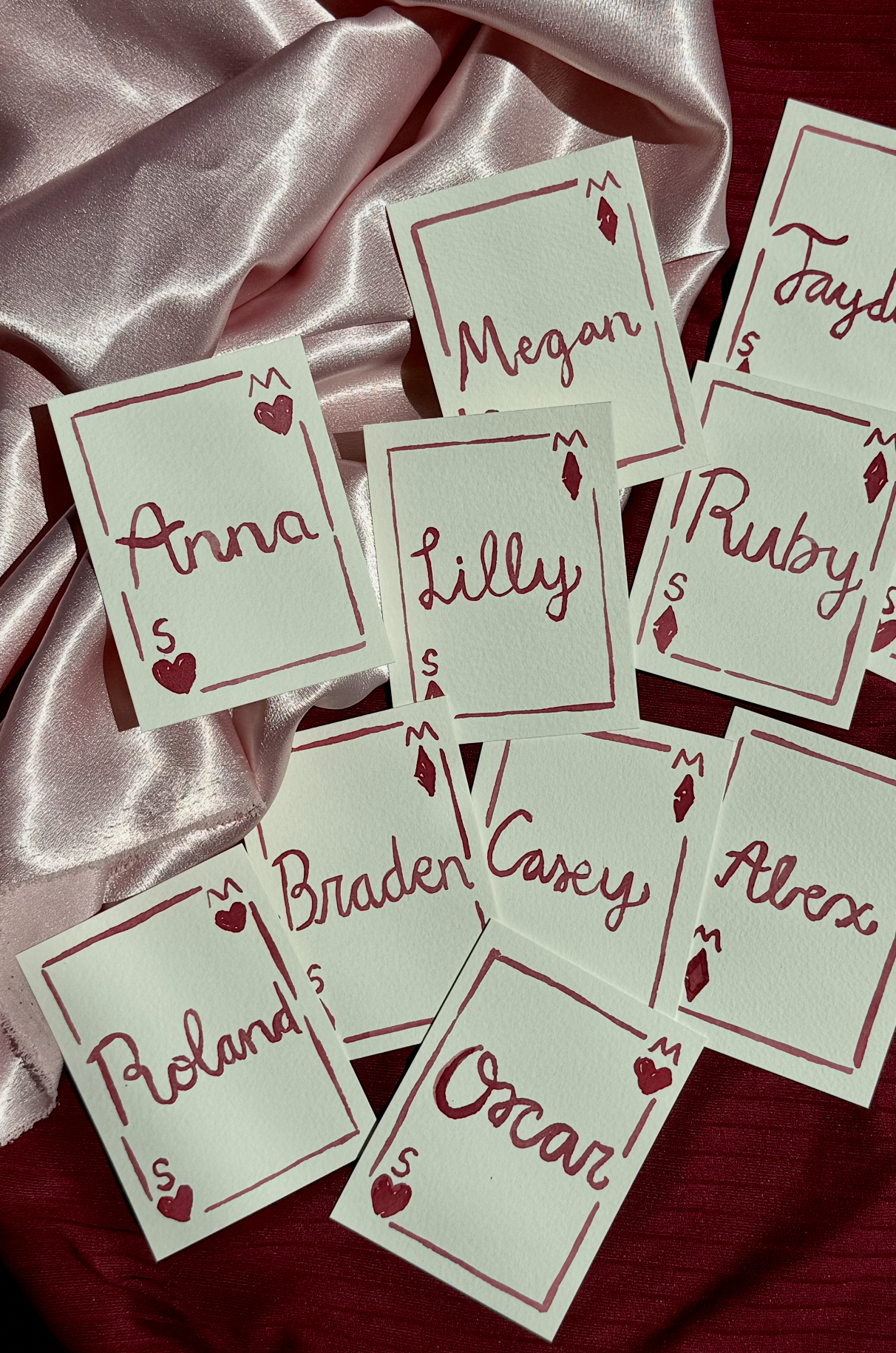 Cards with names of different countries and people, organized on red and pink satin fabric.