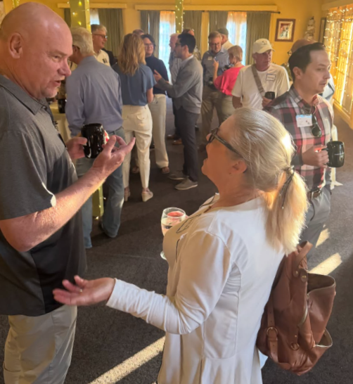 A man and woman talking and holding coffee.