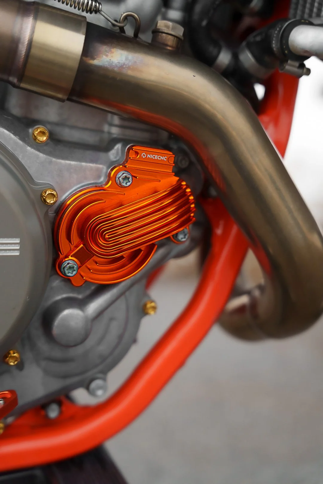 Particolare di un motore di motociclo con un radiatore di colore arancione e tubi di collegamento.