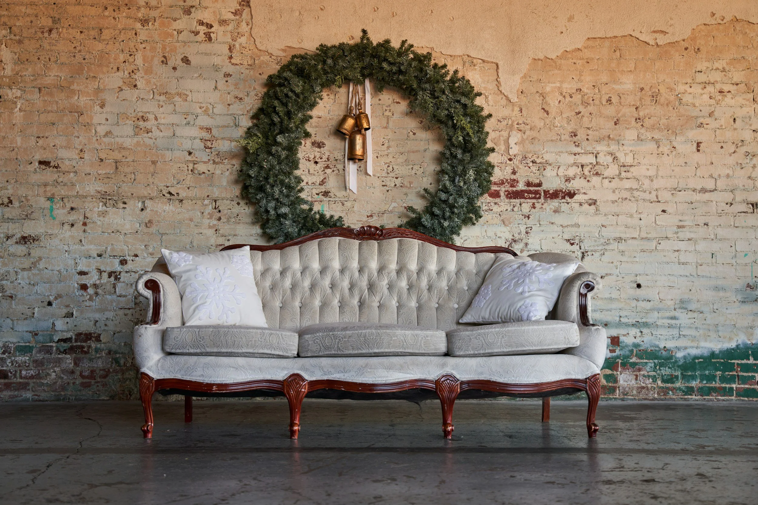 Light colored tuffed antique couch with wood legs.