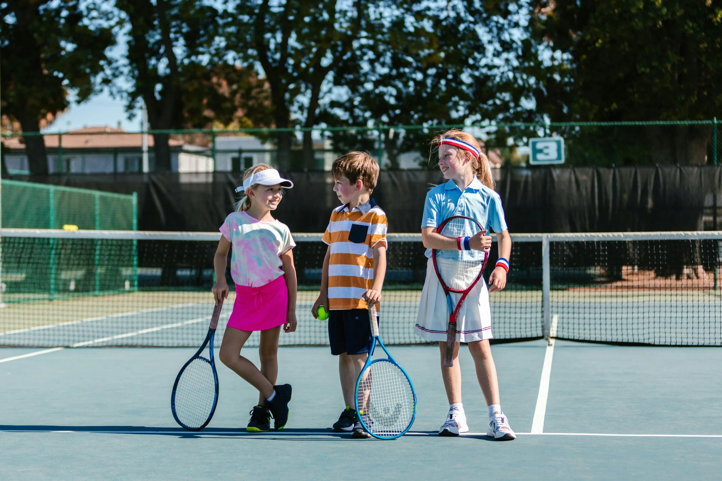 Young kids standing with tennis rackets