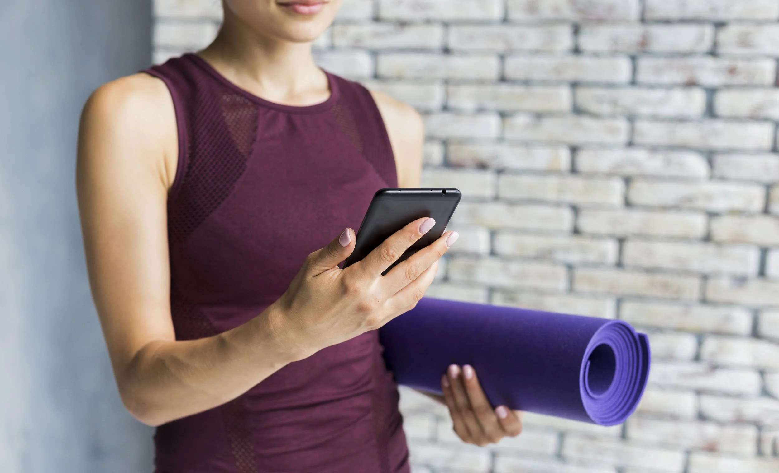 woman-carrying-yoga-mat-while-looking-her-phone.jpg